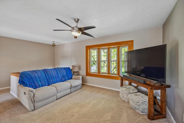 carpeted living area with baseboards and ceiling fan