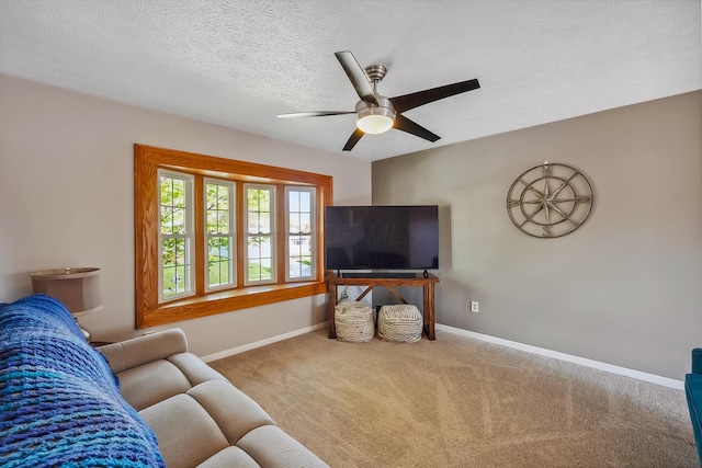 living area with ceiling fan, carpet floors, a textured ceiling, and baseboards