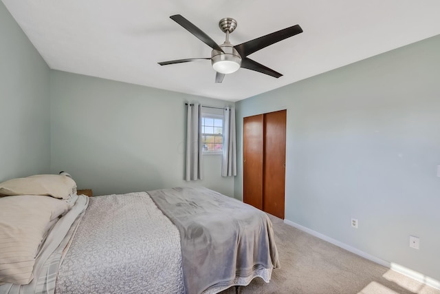 bedroom with baseboards, a closet, a ceiling fan, and light colored carpet