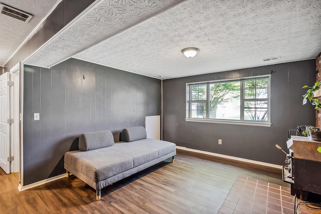 living area featuring a textured ceiling, wood finished floors, and visible vents