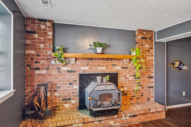 room details with a wood stove, wood finished floors, visible vents, and a textured ceiling