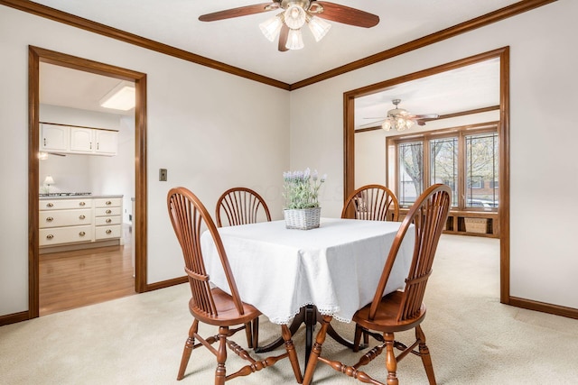 dining room with ornamental molding, baseboards, a ceiling fan, and light colored carpet