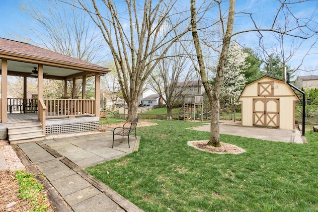 view of yard with a storage shed, a ceiling fan, an outdoor structure, a patio, and fence