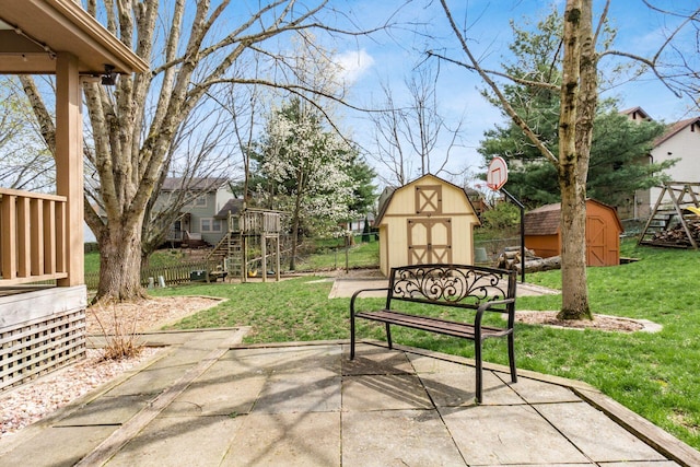view of home's community with a patio, an outdoor structure, fence, a lawn, and a storage unit