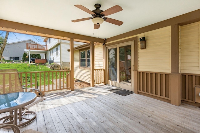 wooden terrace featuring a ceiling fan and a lawn