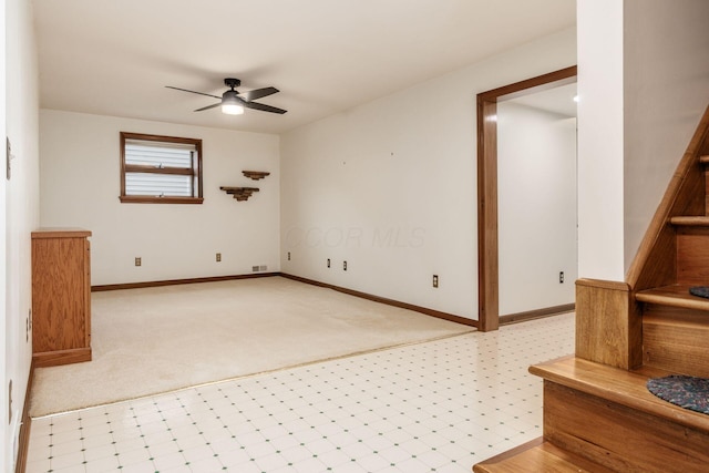 empty room with stairs, baseboards, a ceiling fan, and light floors