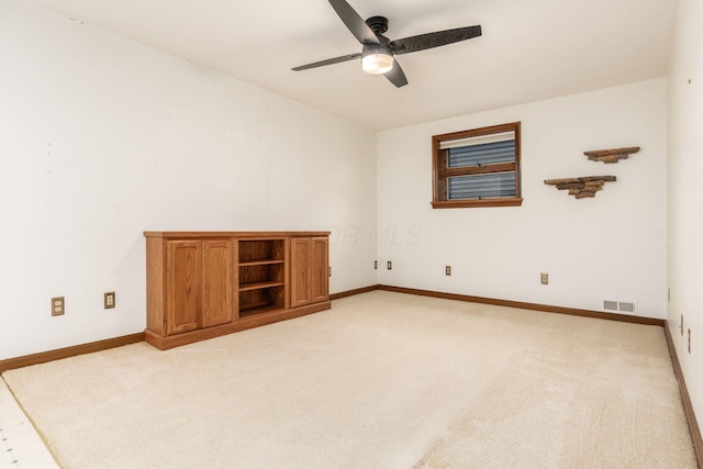 empty room with light colored carpet, baseboards, a ceiling fan, and visible vents