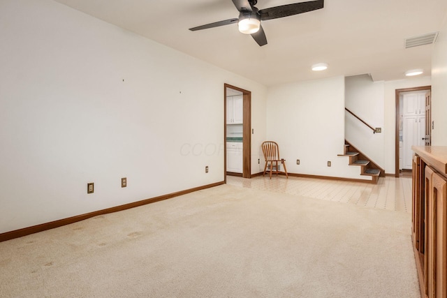 unfurnished room with baseboards, light carpet, a ceiling fan, stairs, and visible vents