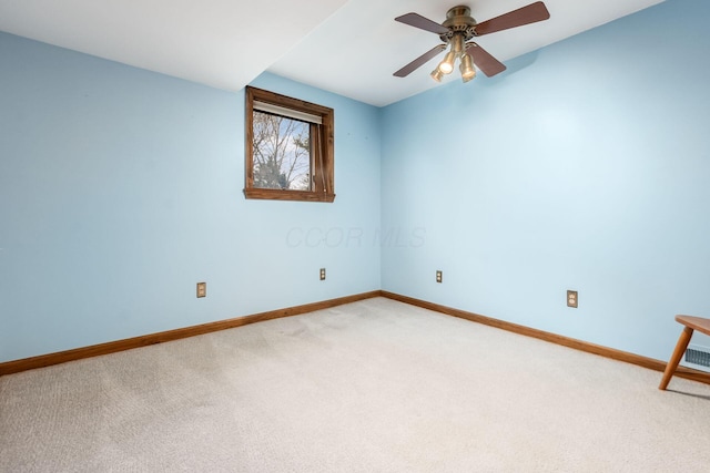 spare room featuring light carpet, baseboards, and a ceiling fan