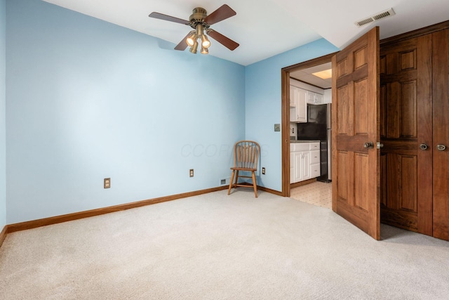 unfurnished bedroom featuring visible vents, baseboards, freestanding refrigerator, and light carpet