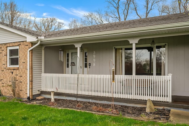 view of exterior entry with brick siding and a porch