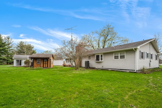 rear view of property with cooling unit, a yard, and an outdoor structure