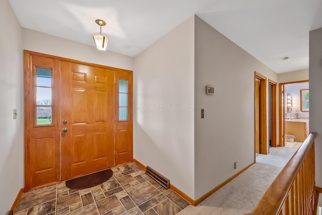 entryway featuring stone finish floor, baseboards, and visible vents
