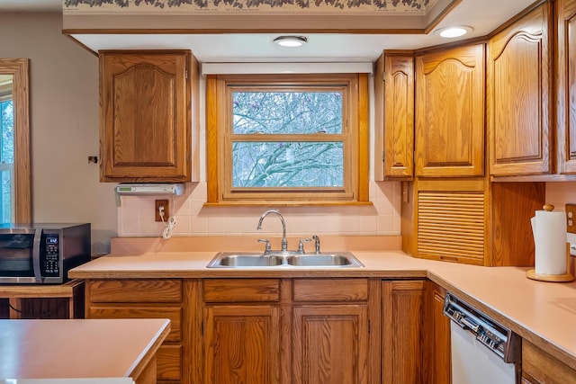 kitchen featuring stainless steel microwave, dishwasher, light countertops, and a sink