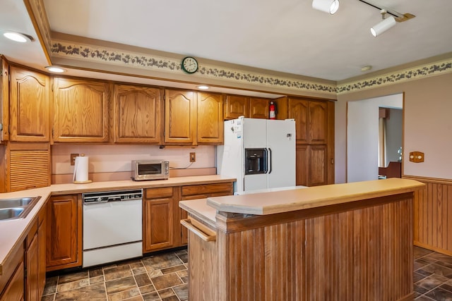 kitchen with brown cabinets, light countertops, a wainscoted wall, and white appliances