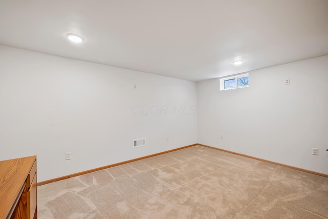 basement featuring light carpet, baseboards, and visible vents