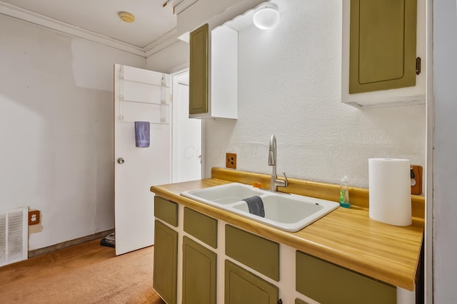 kitchen featuring green cabinets, a sink, light carpet, and visible vents