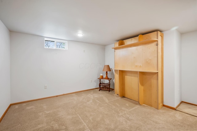 below grade area with baseboards and light colored carpet
