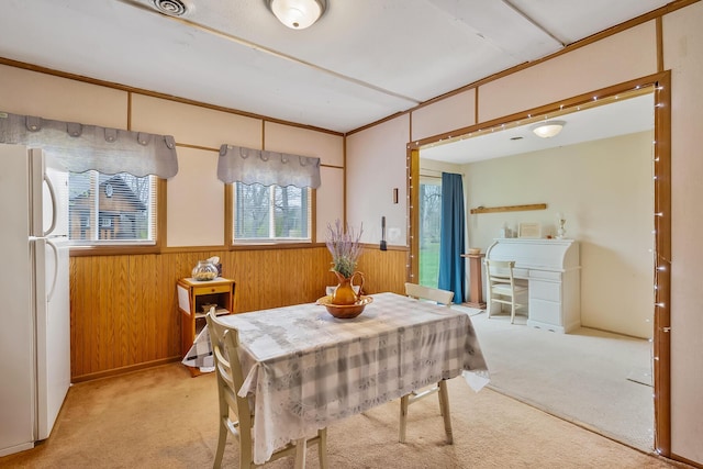 carpeted dining space featuring wood walls and a wainscoted wall