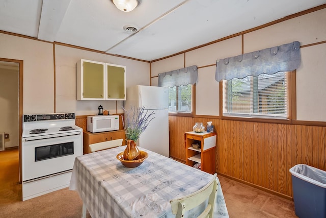 kitchen featuring white appliances, light colored carpet, visible vents, wood walls, and wainscoting