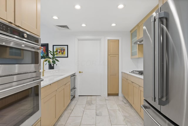 kitchen with appliances with stainless steel finishes, a sink, light countertops, recessed lighting, and visible vents