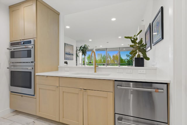 kitchen featuring a sink, appliances with stainless steel finishes, light brown cabinetry, and recessed lighting