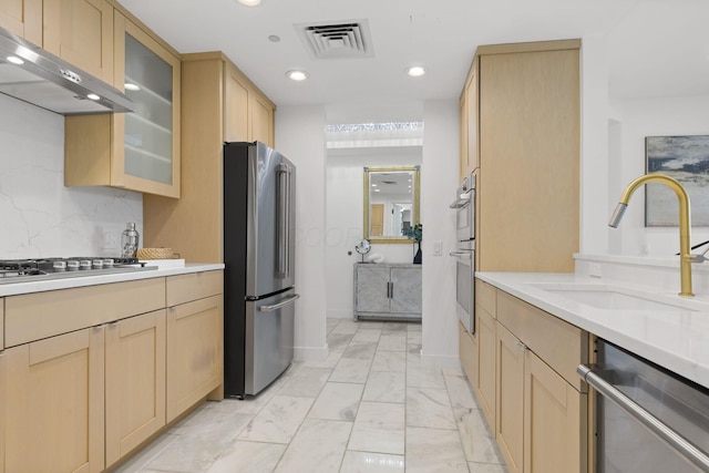 kitchen featuring a sink, appliances with stainless steel finishes, under cabinet range hood, and light brown cabinetry