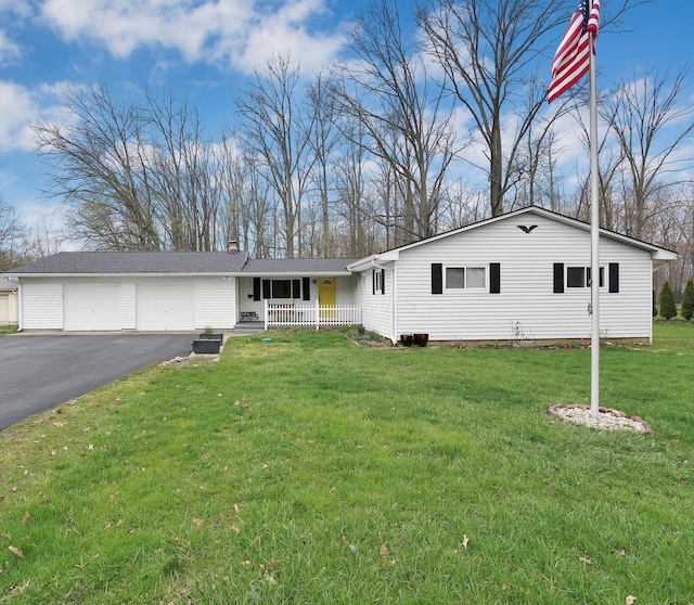 ranch-style house featuring a front lawn, an attached garage, a chimney, a porch, and driveway