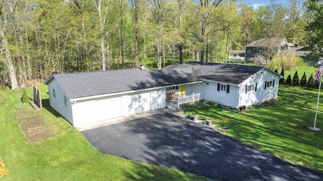 ranch-style home with roof with shingles, an attached garage, driveway, and a front yard