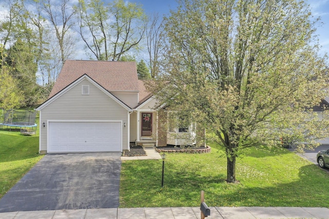 ranch-style home with a trampoline, aphalt driveway, a front lawn, and an attached garage