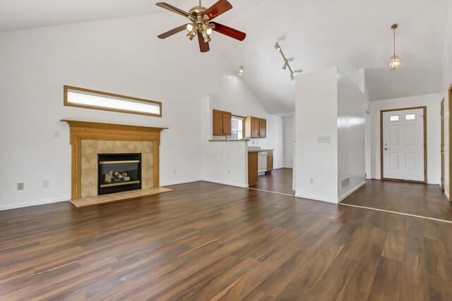 unfurnished living room featuring dark wood-style floors, a tiled fireplace, high vaulted ceiling, ceiling fan, and baseboards