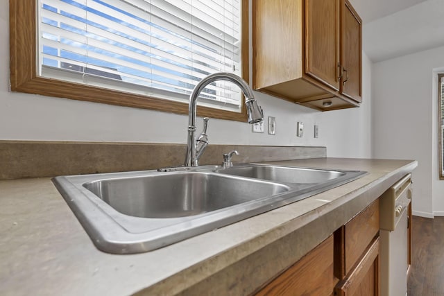 kitchen featuring a healthy amount of sunlight, dishwasher, brown cabinetry, and a sink