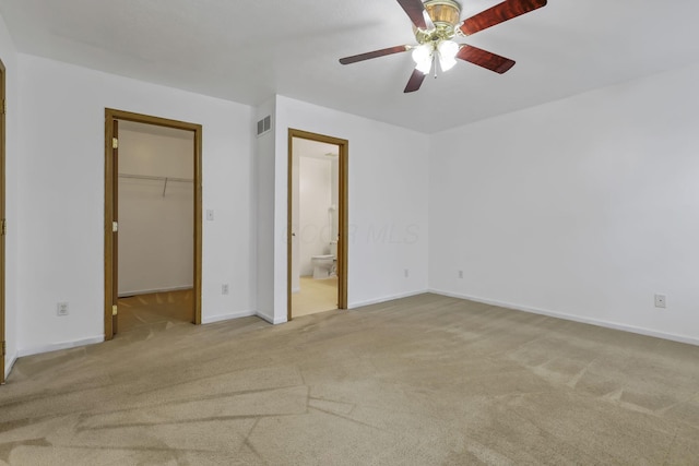 unfurnished bedroom with a walk in closet, visible vents, ensuite bathroom, and carpet flooring