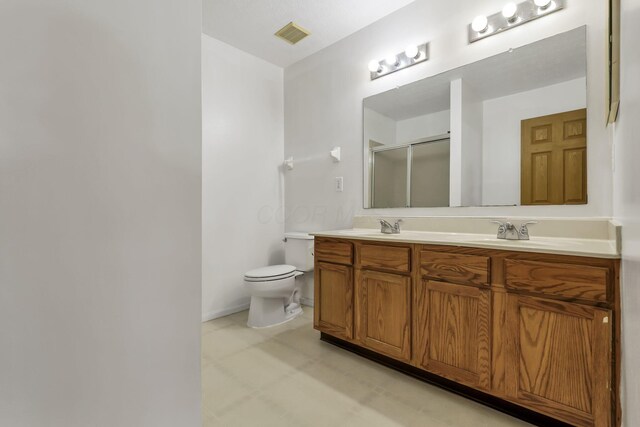 bathroom featuring tile patterned floors, double vanity, toilet, a sink, and a stall shower