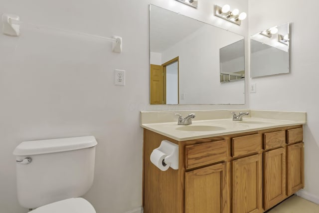 bathroom with double vanity, toilet, and a sink