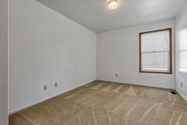 empty room with baseboards, visible vents, and carpet