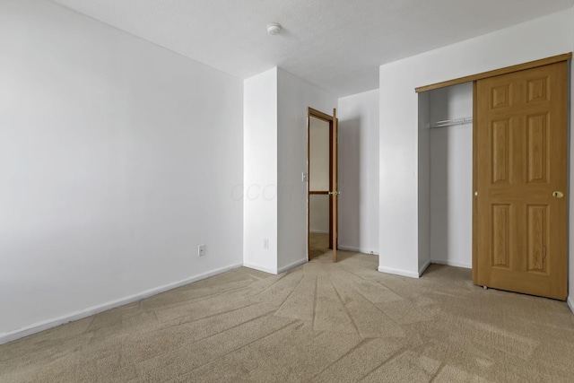 unfurnished bedroom featuring baseboards, a closet, and carpet