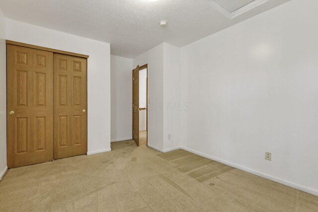 unfurnished bedroom with a closet, light colored carpet, and baseboards