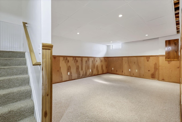 finished basement with wood walls, carpet, stairway, and wainscoting