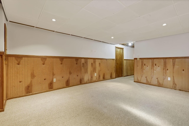 finished below grade area with recessed lighting, a wainscoted wall, wood walls, and carpet