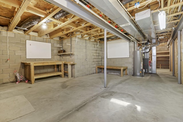 unfinished basement featuring a workshop area, concrete block wall, heating unit, and gas water heater