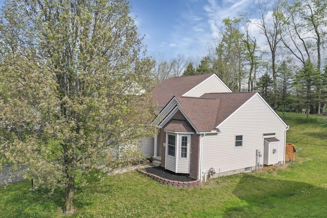 view of side of home with a yard and a shingled roof