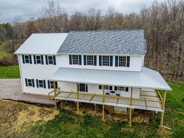 view of front of house featuring a front yard, a deck, and a forest view