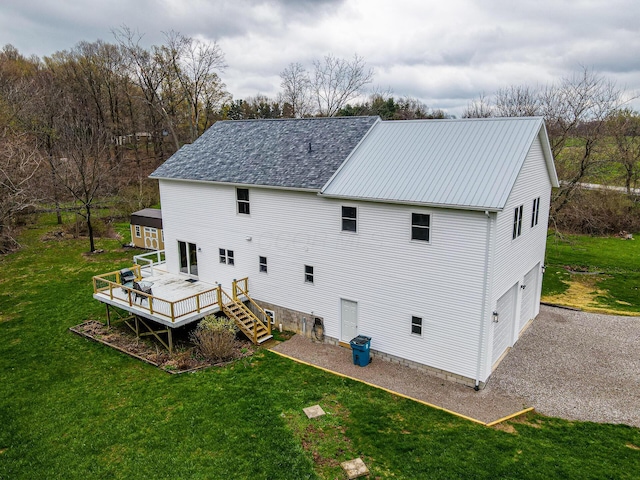 rear view of house featuring stairway, a lawn, metal roof, an attached garage, and a deck