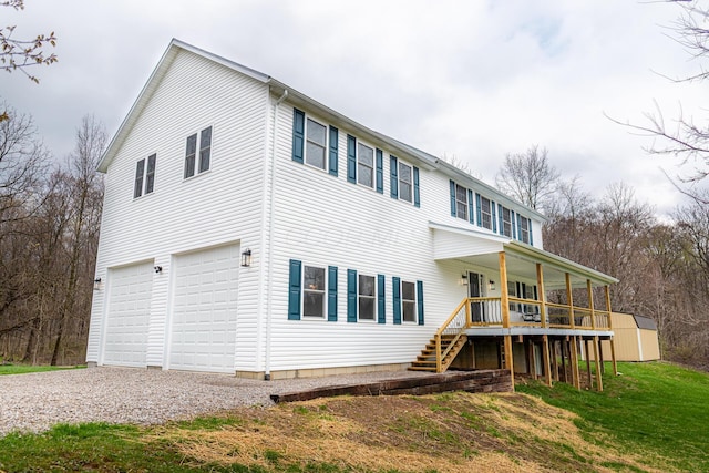 view of front of home with a garage, an outdoor structure, stairway, a storage unit, and driveway