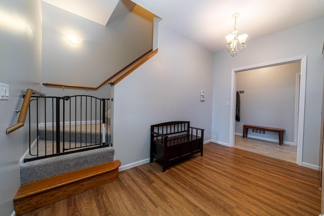 interior space with a chandelier, wood finished floors, baseboards, and stairway