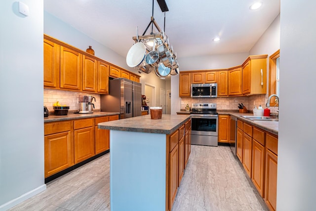 kitchen with tasteful backsplash, a kitchen island, appliances with stainless steel finishes, a sink, and dark countertops