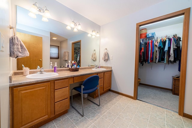 full bathroom featuring baseboards, double vanity, a sink, and a walk in closet