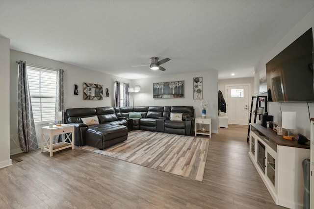 living room featuring ceiling fan, baseboards, and wood finished floors