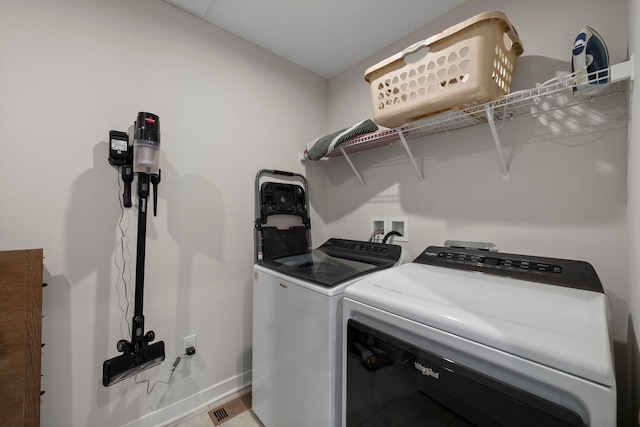 washroom featuring washing machine and dryer, baseboards, and laundry area